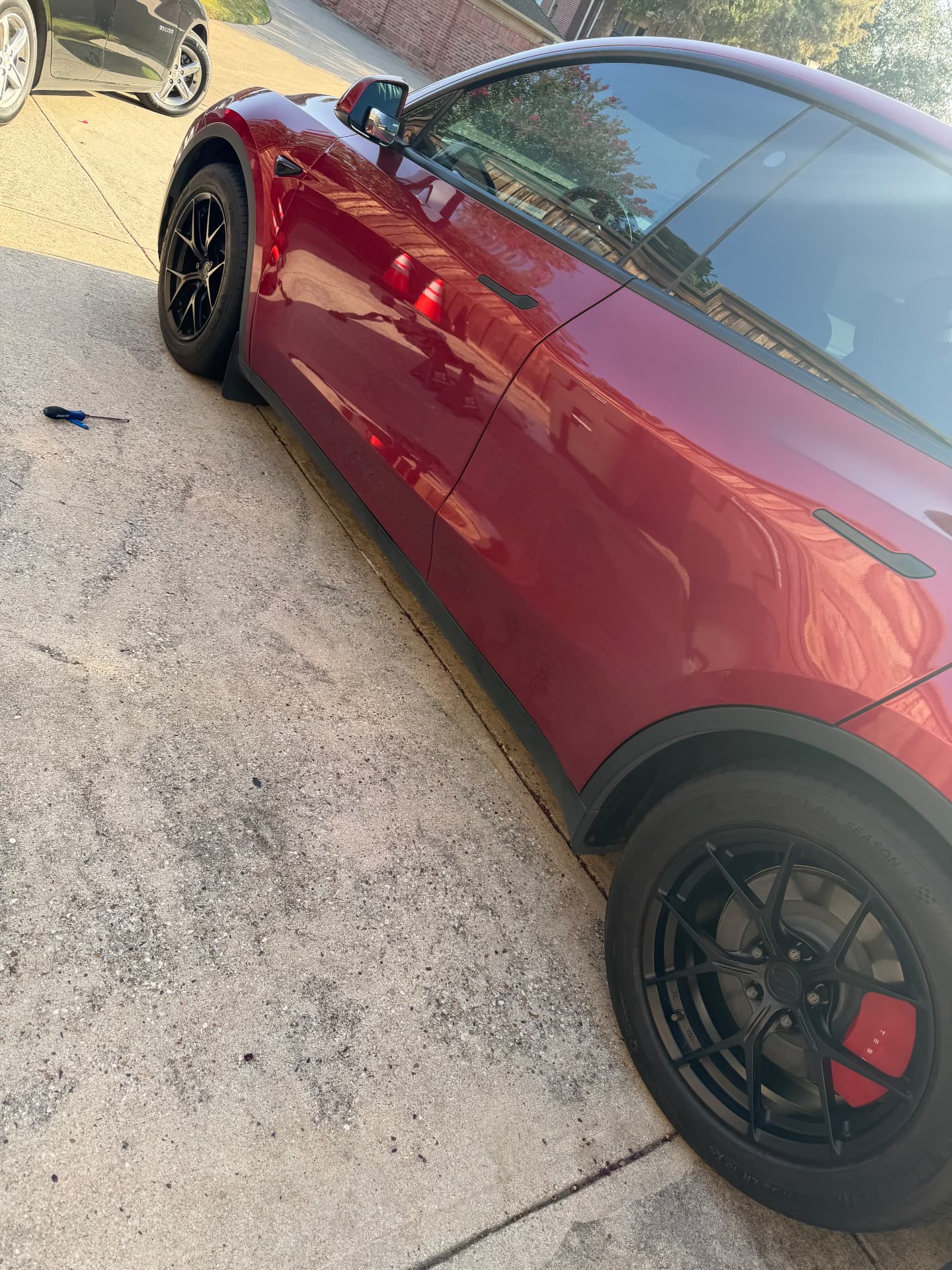 Red Tesla Model Y back on the ground with a new wheel fitted and torqued after a completed mobile EV tire service call